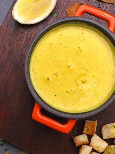 A bowl of soup with bread and lemon slices